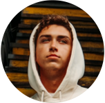 Profile photo of a young person wearing a white hoodie, standing in front of yellow and black stairs.